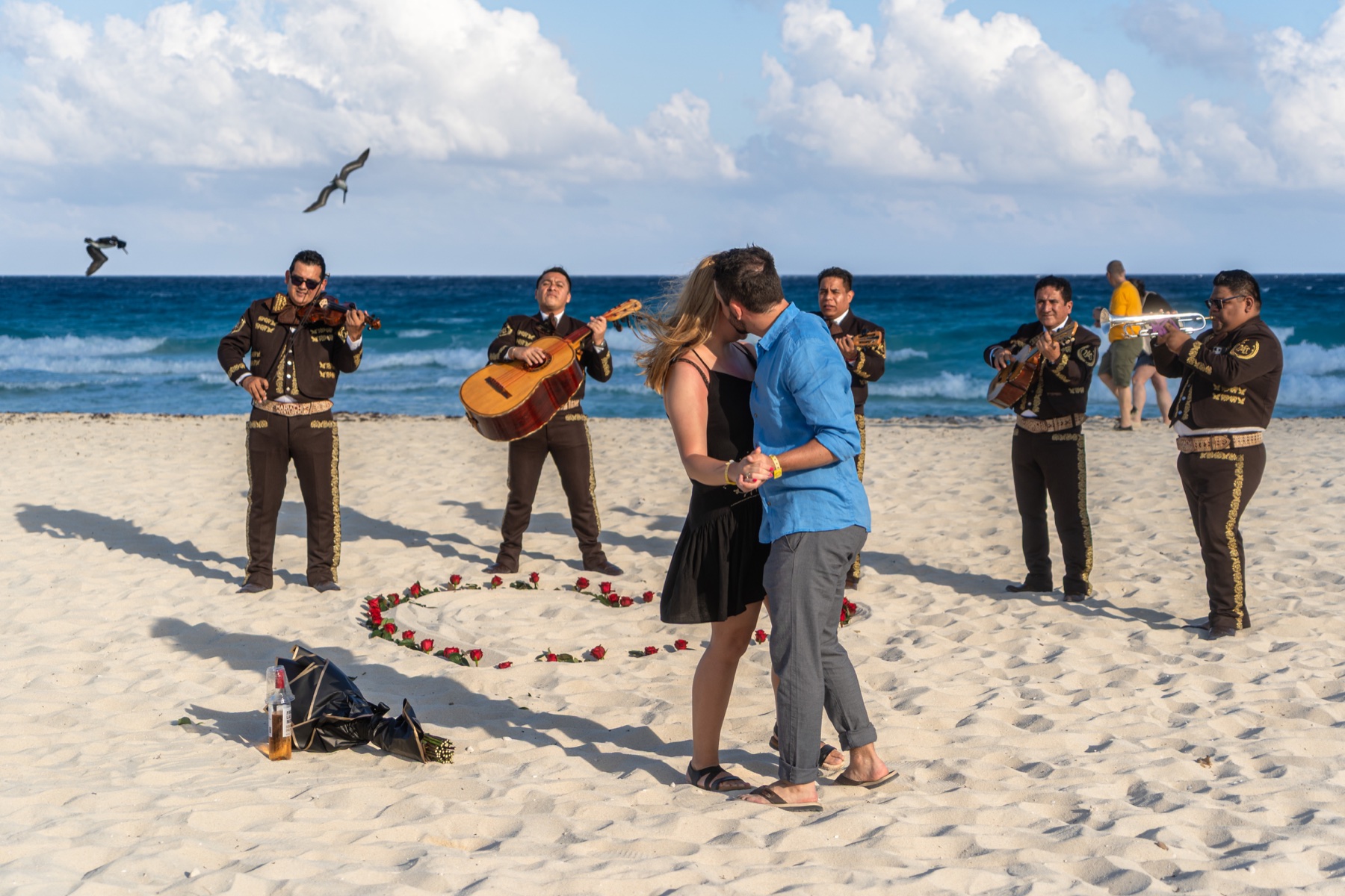 Pareja bailando con mariachi frente al mar
