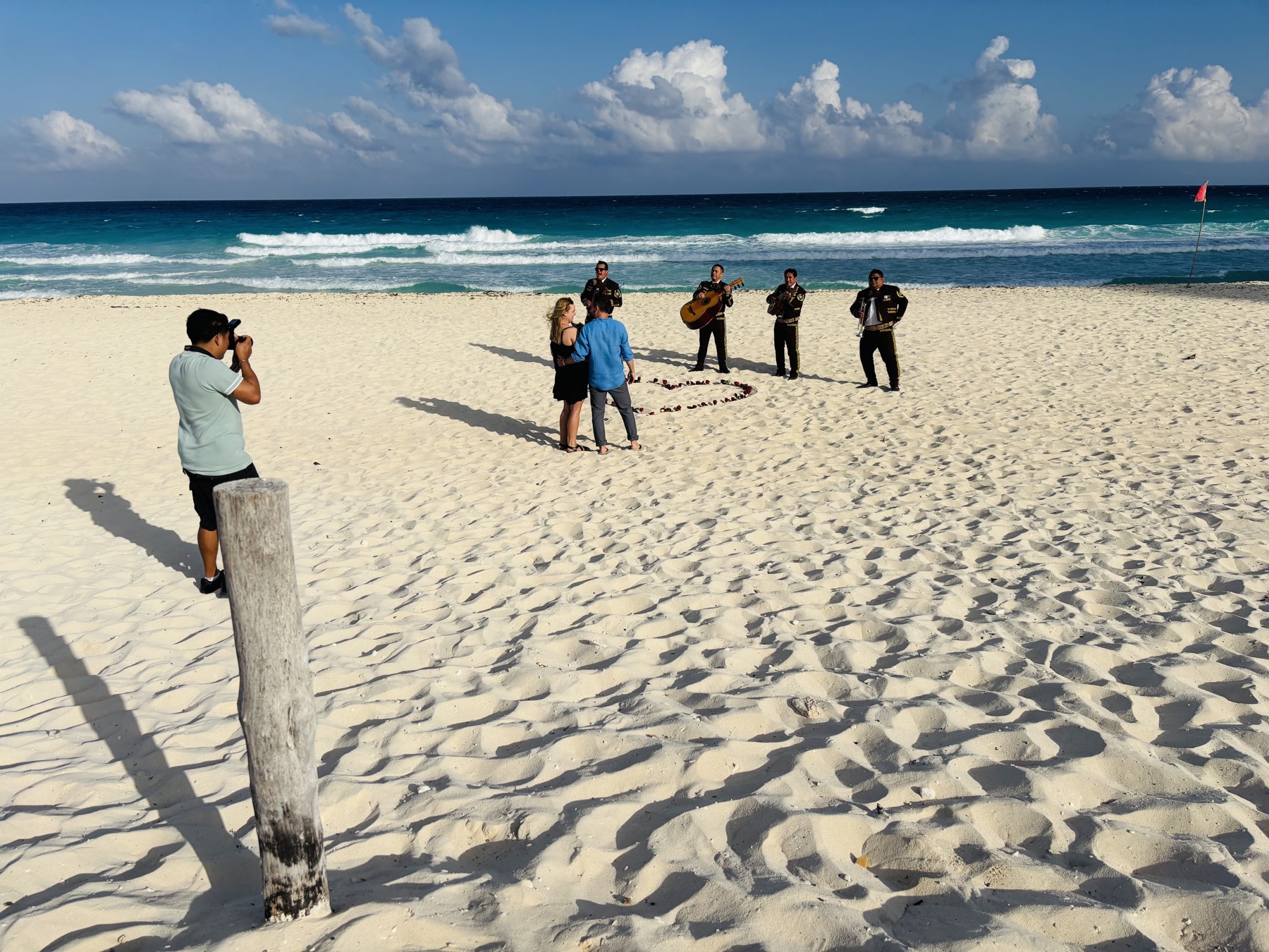 Photographer, couple and mariachi during a beach proposal