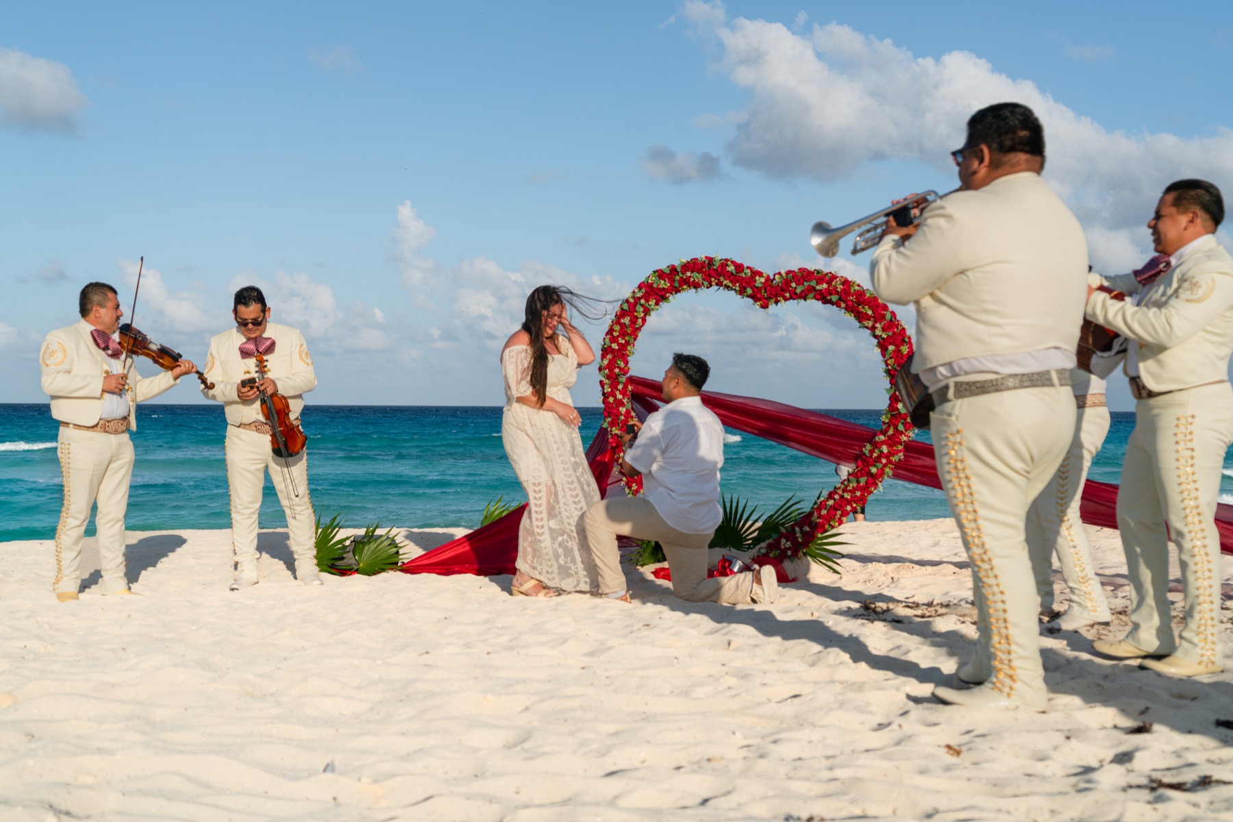 Propuesta de matrimonio con arco de rosas y mariachi en la playa